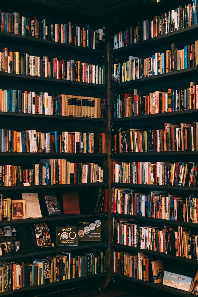 Corner view of a library with dark wooden bookshelves filled with a variety of books.